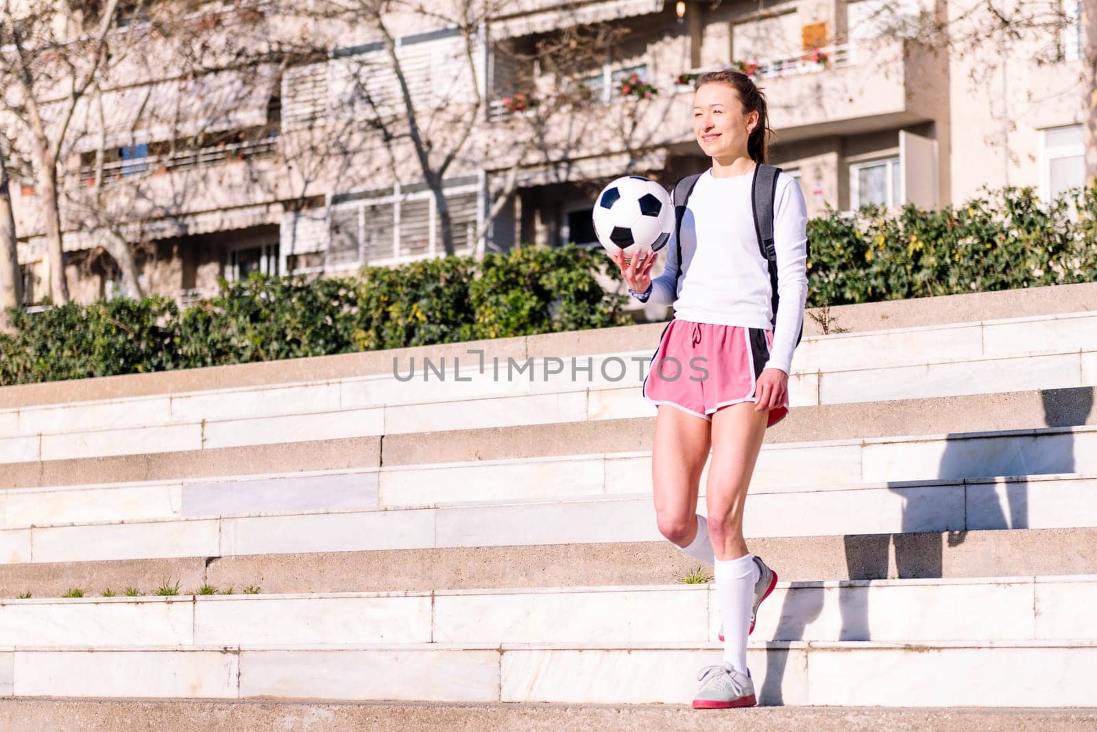 smiling caucasian woman walking at park with a soccer ball in hand, concept of sport and active lifestyle, copy space for text