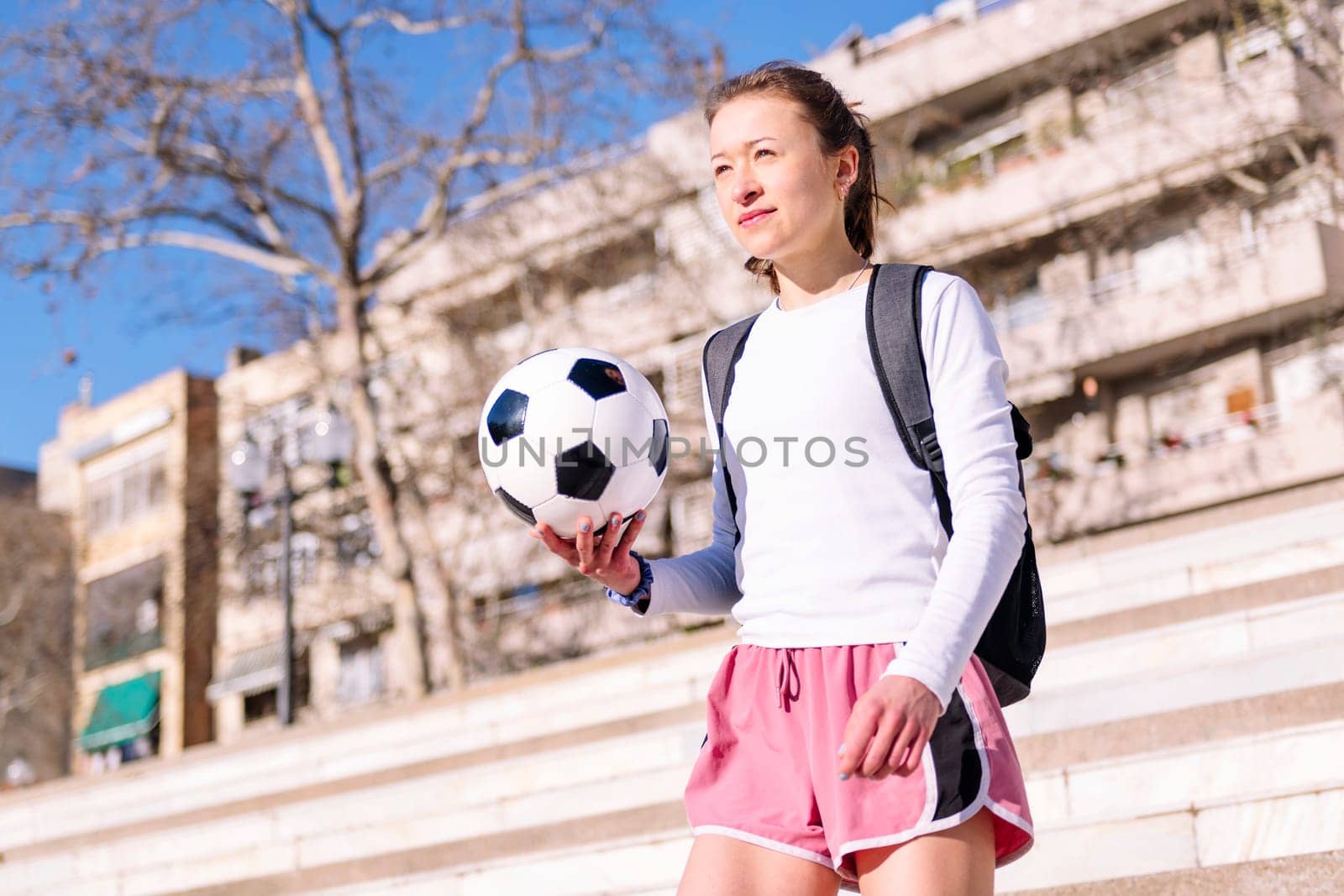 caucasian woman walking at city with a soccer ball in hand, concept of sport and active lifestyle, copy space for text