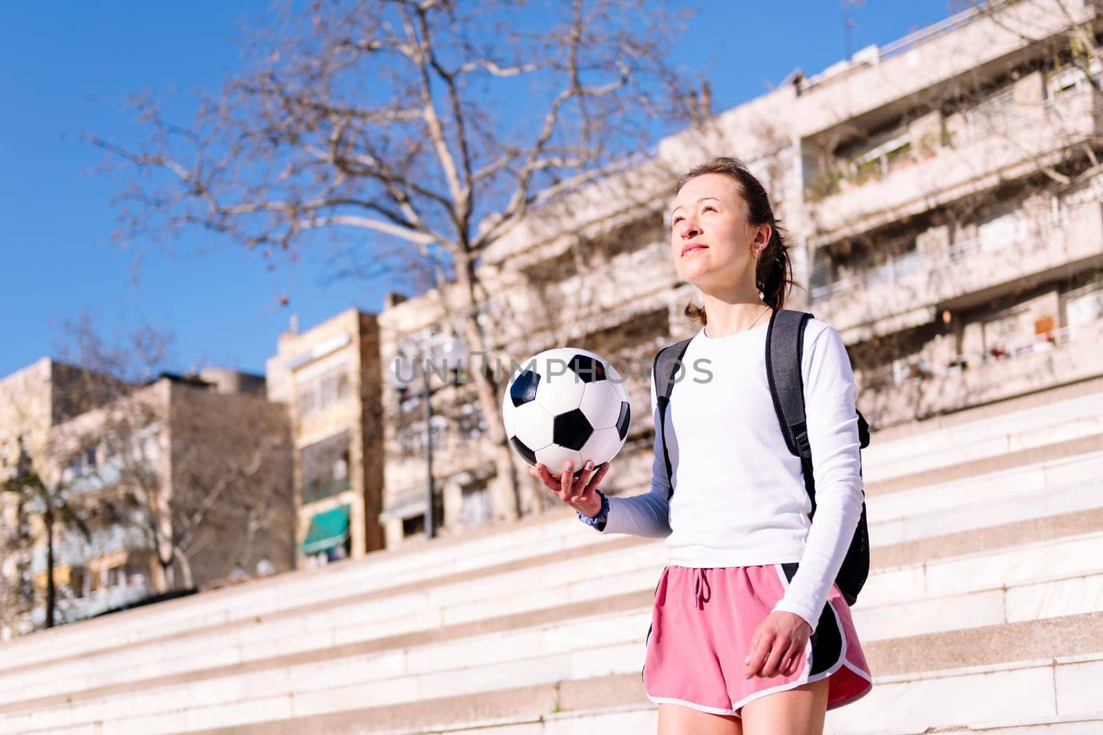 young caucasian woman walking at city with a soccer ball in hand, concept of sport and active lifestyle, copy space for text