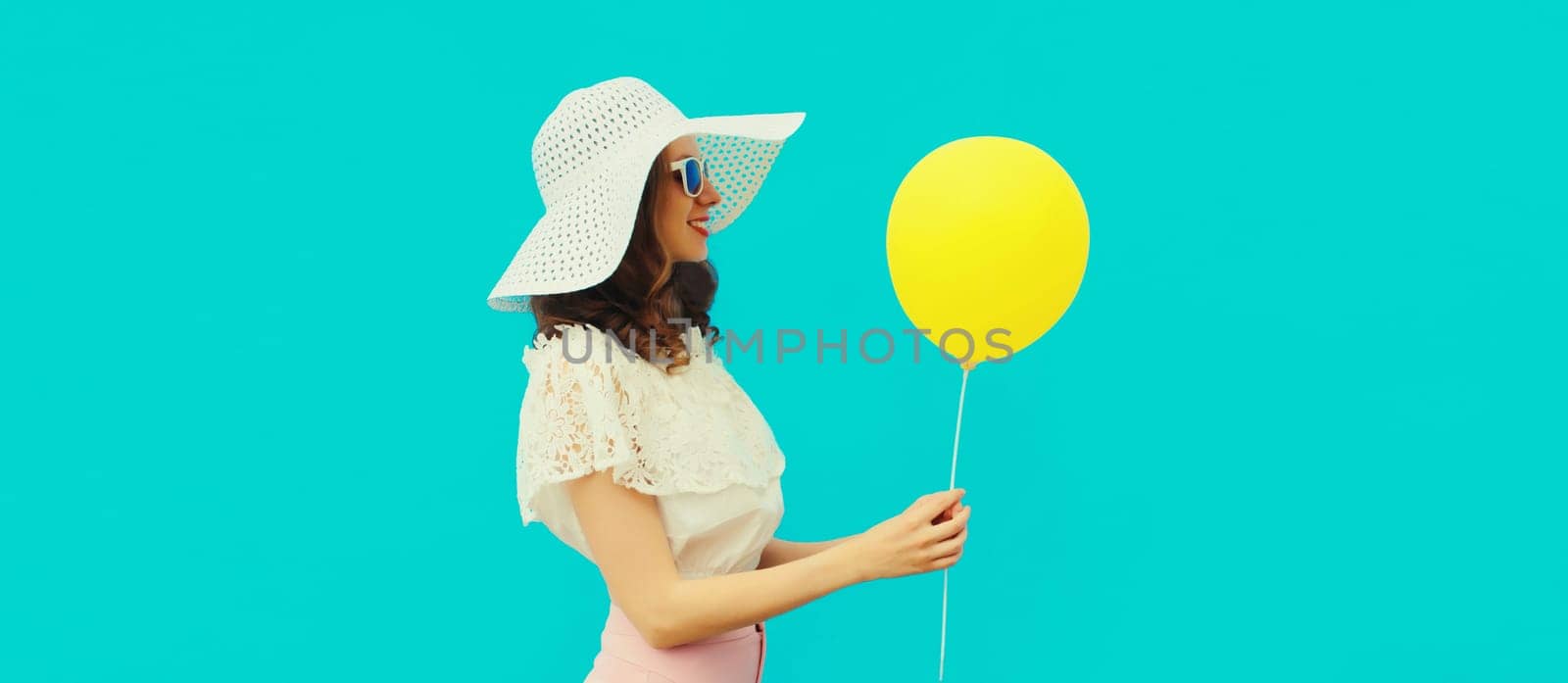 Summer portrait of happy young woman with yellow balloon on blue studio background by Rohappy