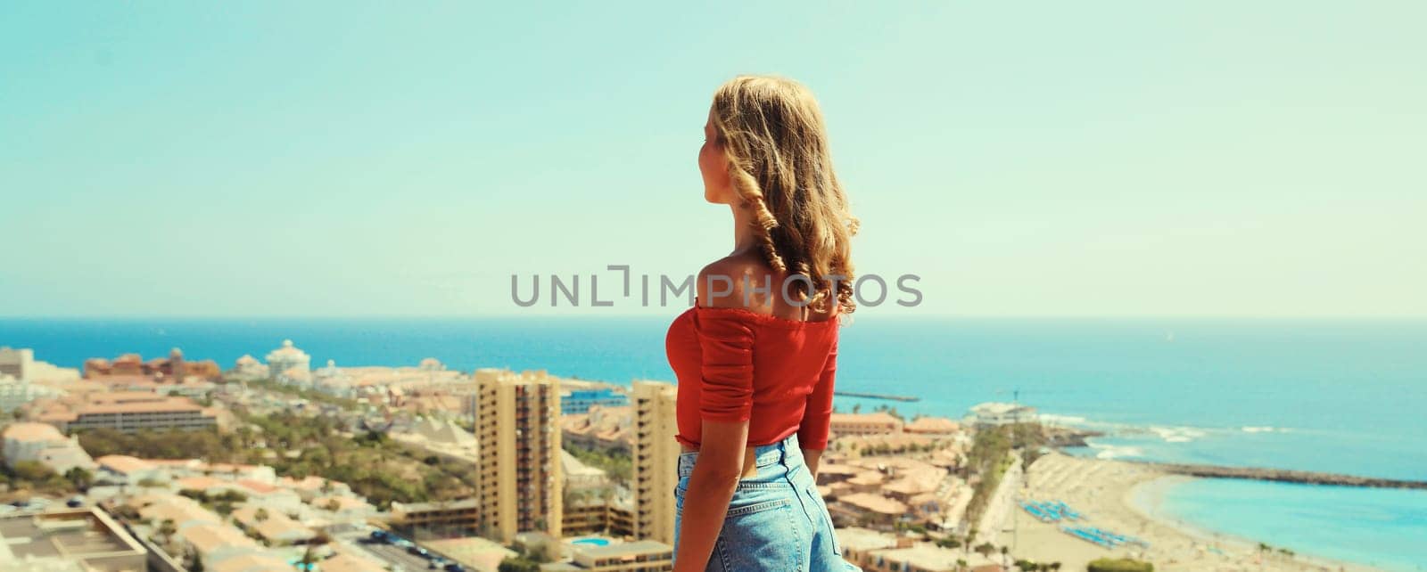 Summer vacation, beautiful young woman tourist on top of the mountain looking around the city in Tenerife, Canary Islands, Spain. Aerial top view.