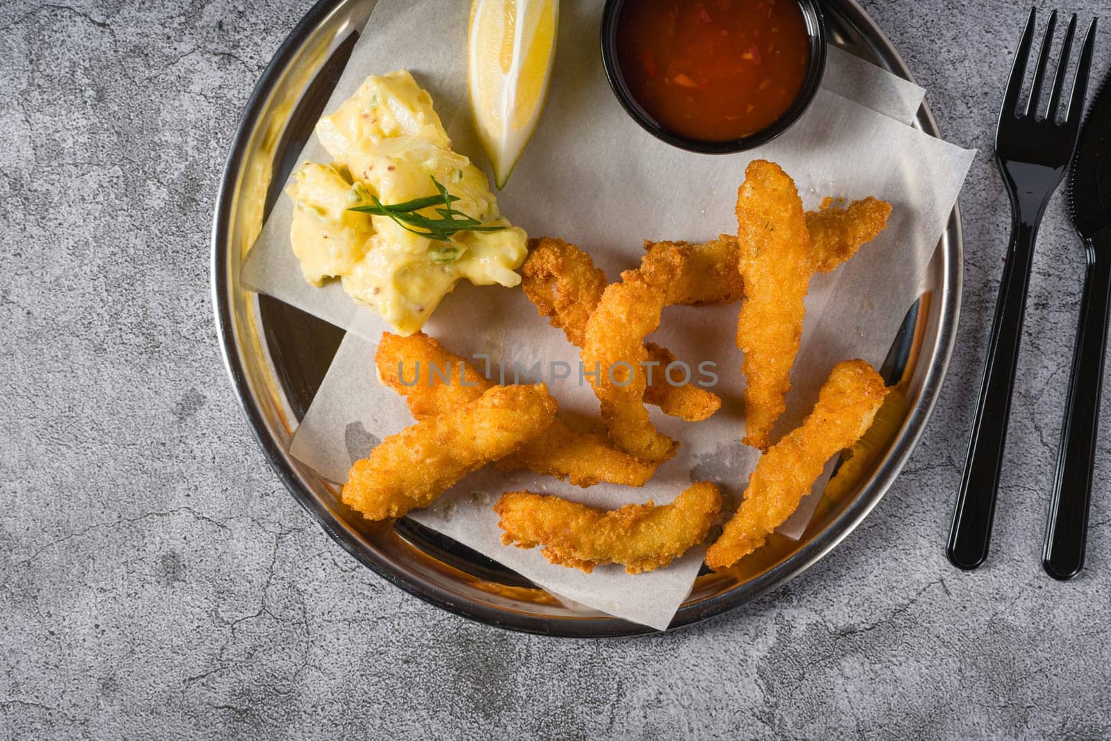 Deep fried shrimp tempura with potato salad on a metal plate