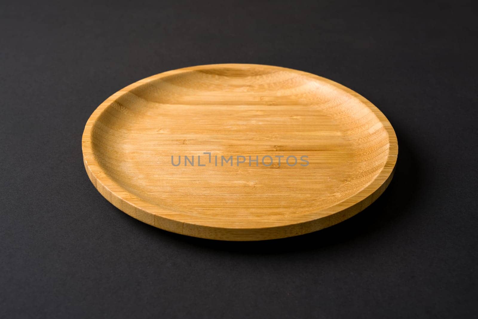 Wooden plate on dark gray background. handmade kitchen utensils by Sonat