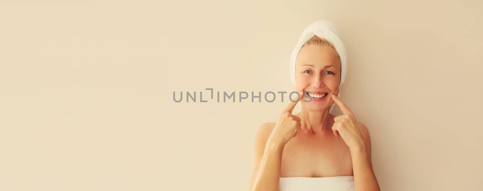 Happy smiling caucasian middle-aged woman points to her white clean teeth in the morning at home by Rohappy
