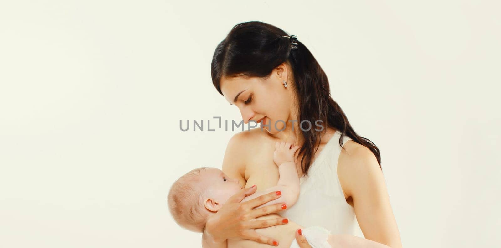 Happy young mother breastfeeding her baby on white background