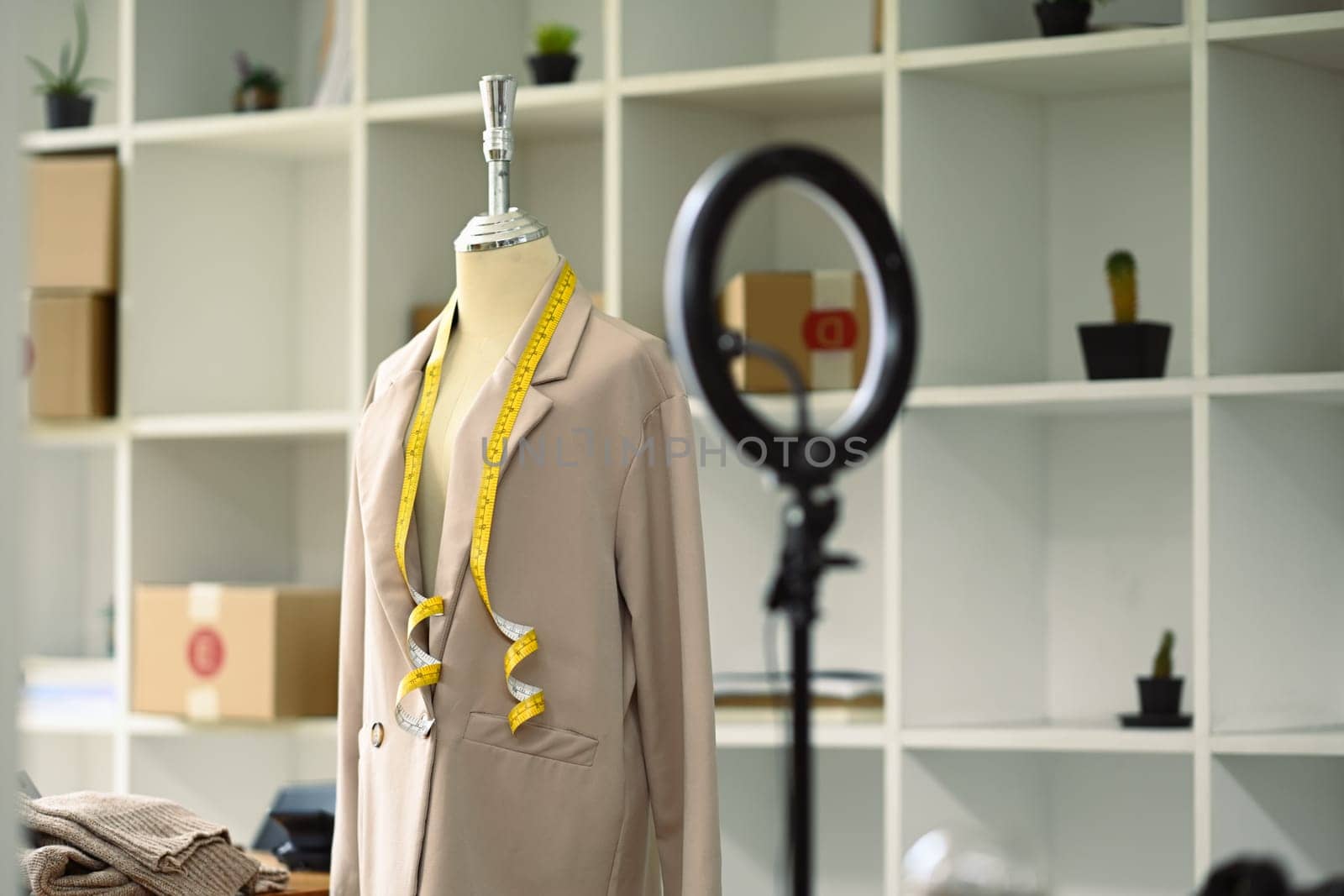 Mannequin with a beige suit and LED ring light in tailors studio. Small business and designer concept.