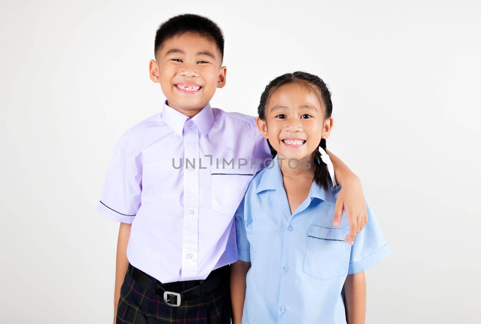 Portrait two smile Asian little girl kindergarten and boy primary posing studio isolated white background, happy cute woman and man kid brother sister wear school uniform plaid, back to school concept