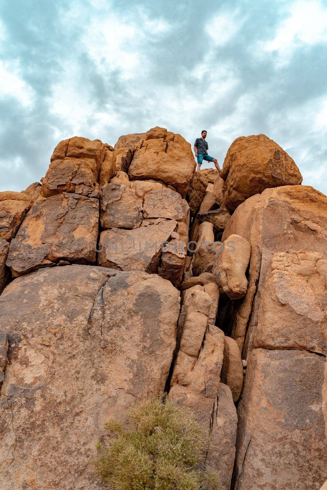 Young man on top of Joshua Tree rocks feeling free in the amazing landscape. . High quality photo