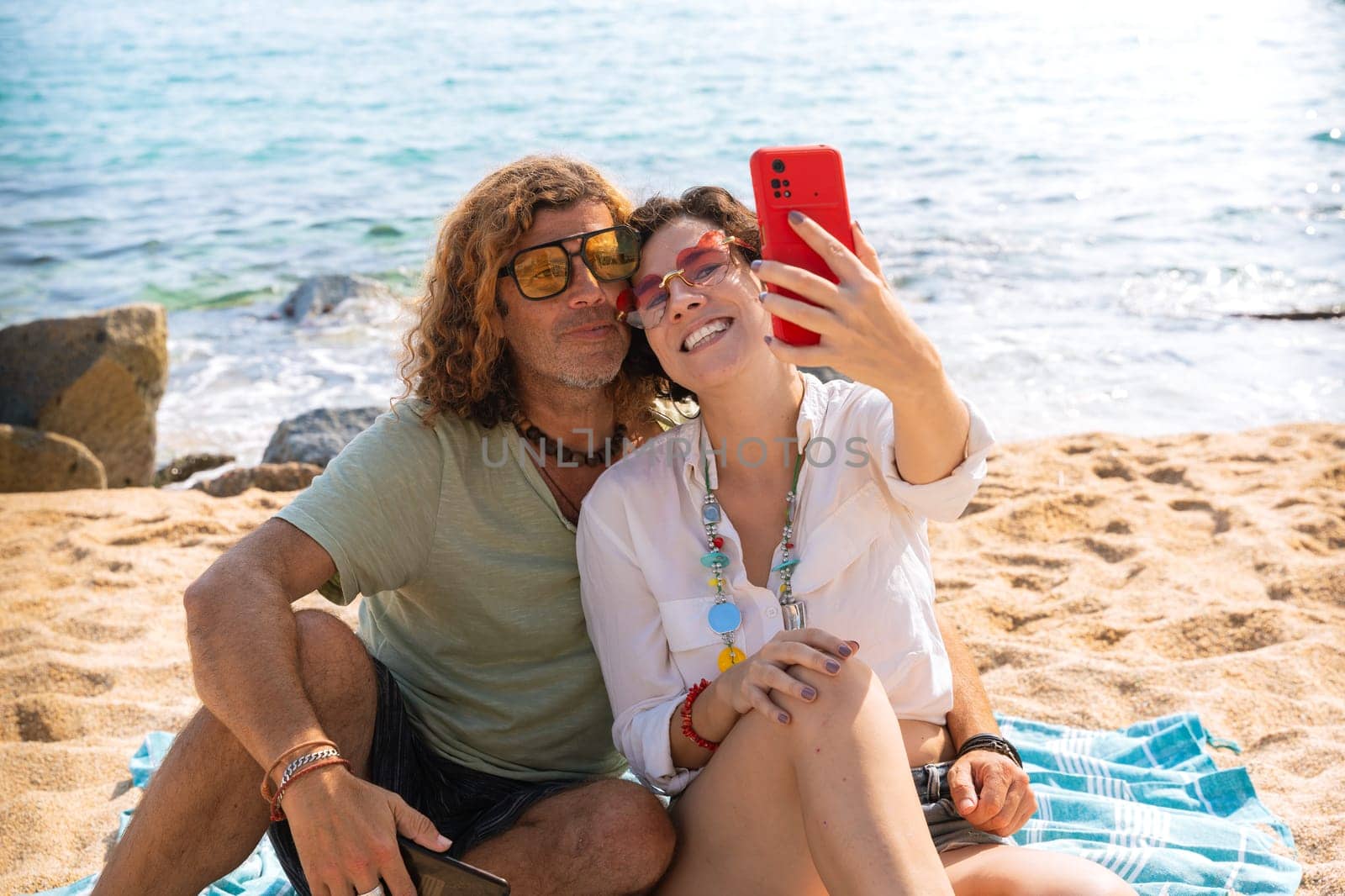 Happy couple takes a selfie together with smartphone on the beach by mariaphoto3