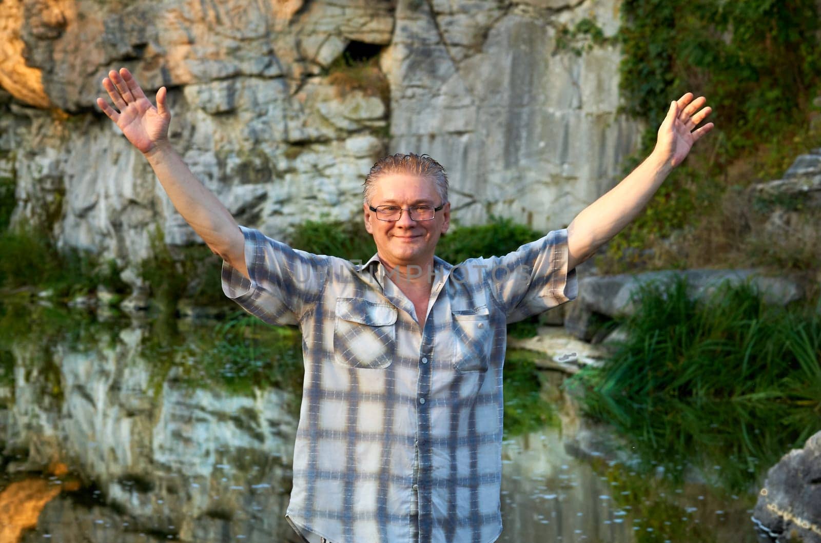 Cheerful smiling man tourist stands on a mountain river canyon by jovani68