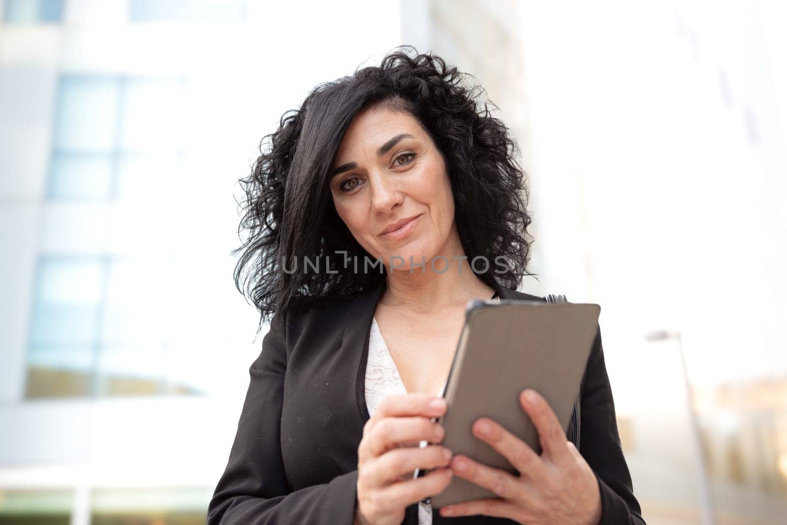 Smiling caucasian businesswoman with digital tablet outdoors. by mariaphoto3