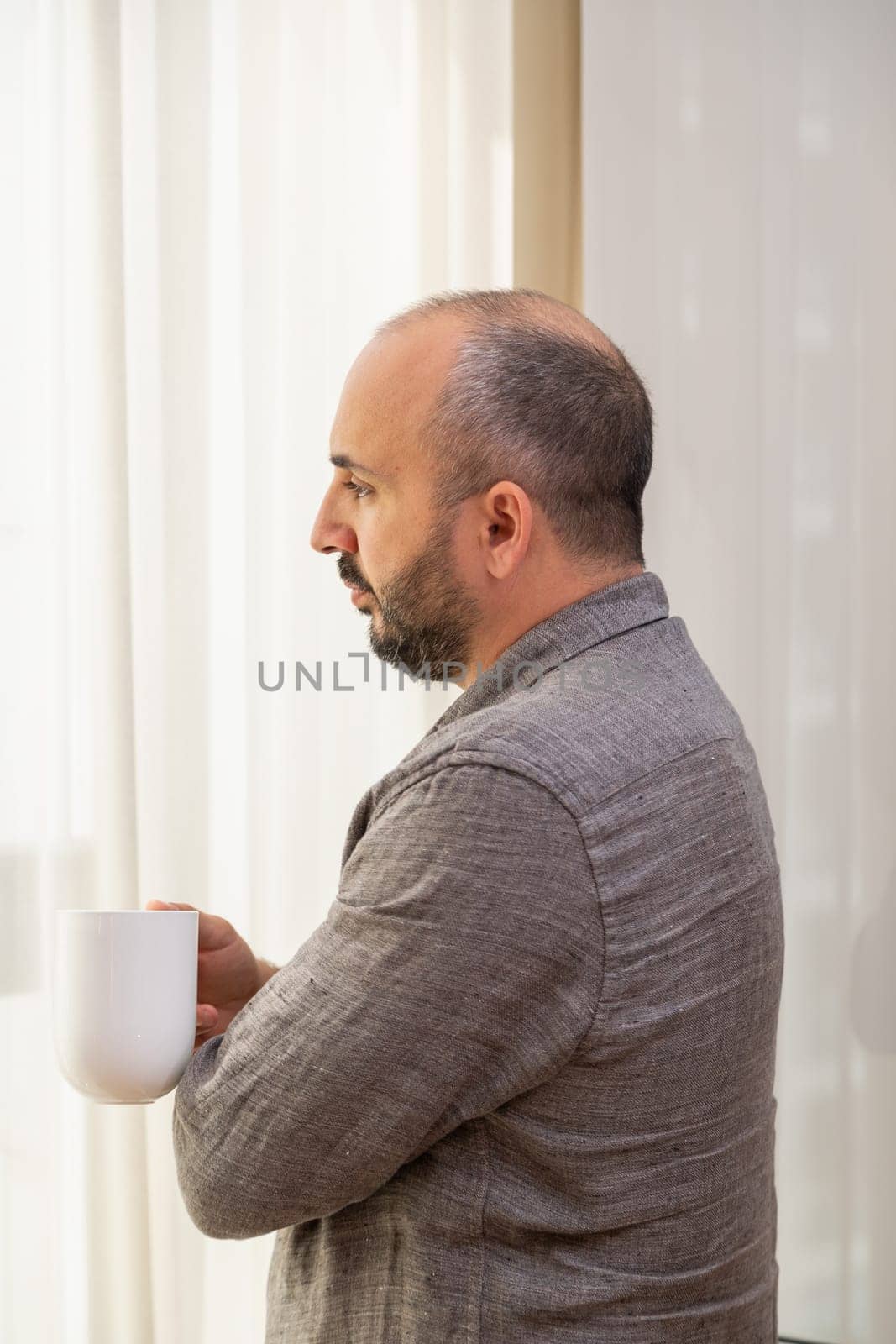 A man enjoys his morning coffee by the window