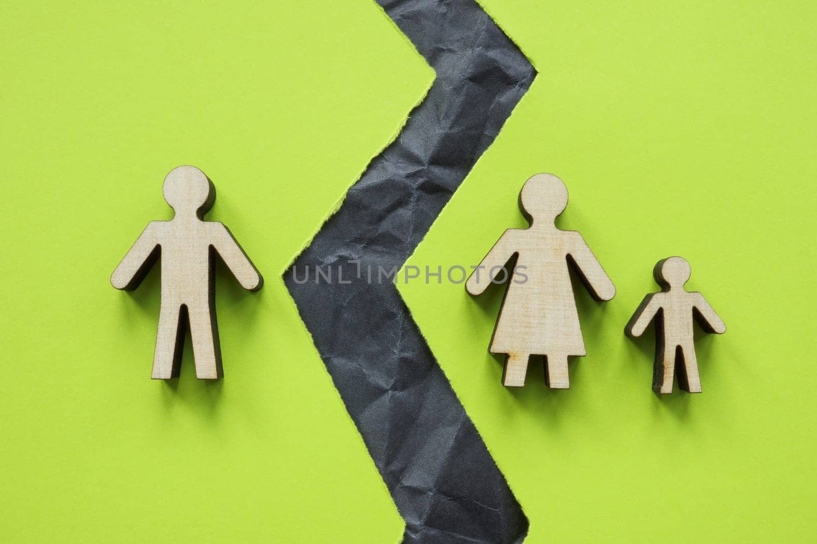 Divided family figures and a torn sheet as symbol of divorce.