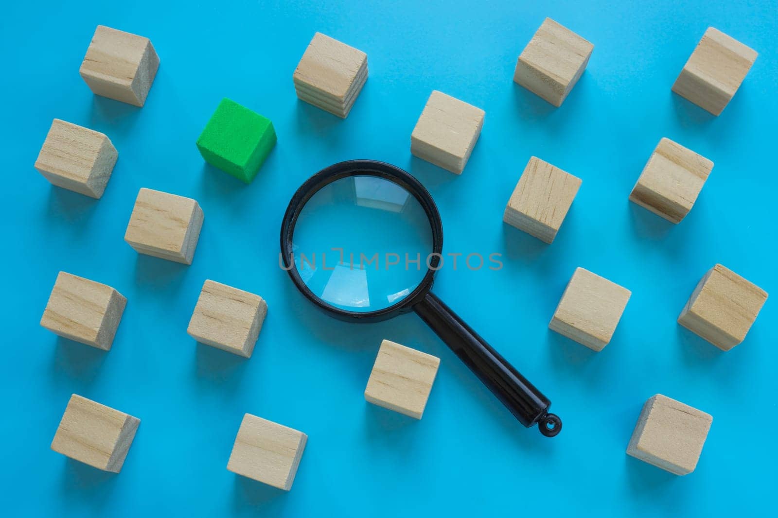 Cubes and a magnifying glass. Talent acquisition or new employee.