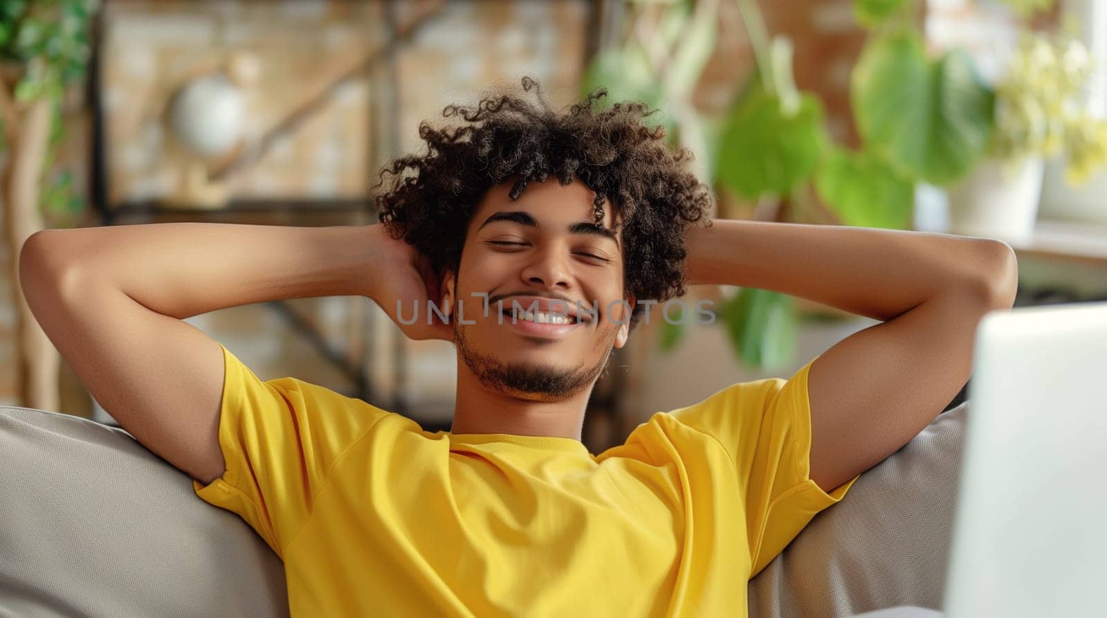 Happy relaxed african young man enjoying sitting at desk during working at the laptop at home with green plants, female freelancer or student resting