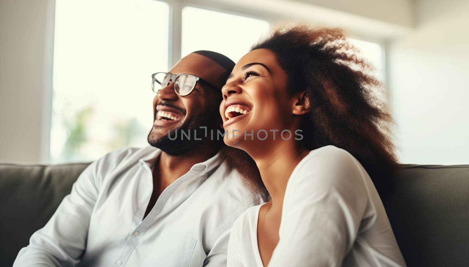 Portrait of happy smiling african young couple hugging, cheerful black woman and man sitting on sofa at home together