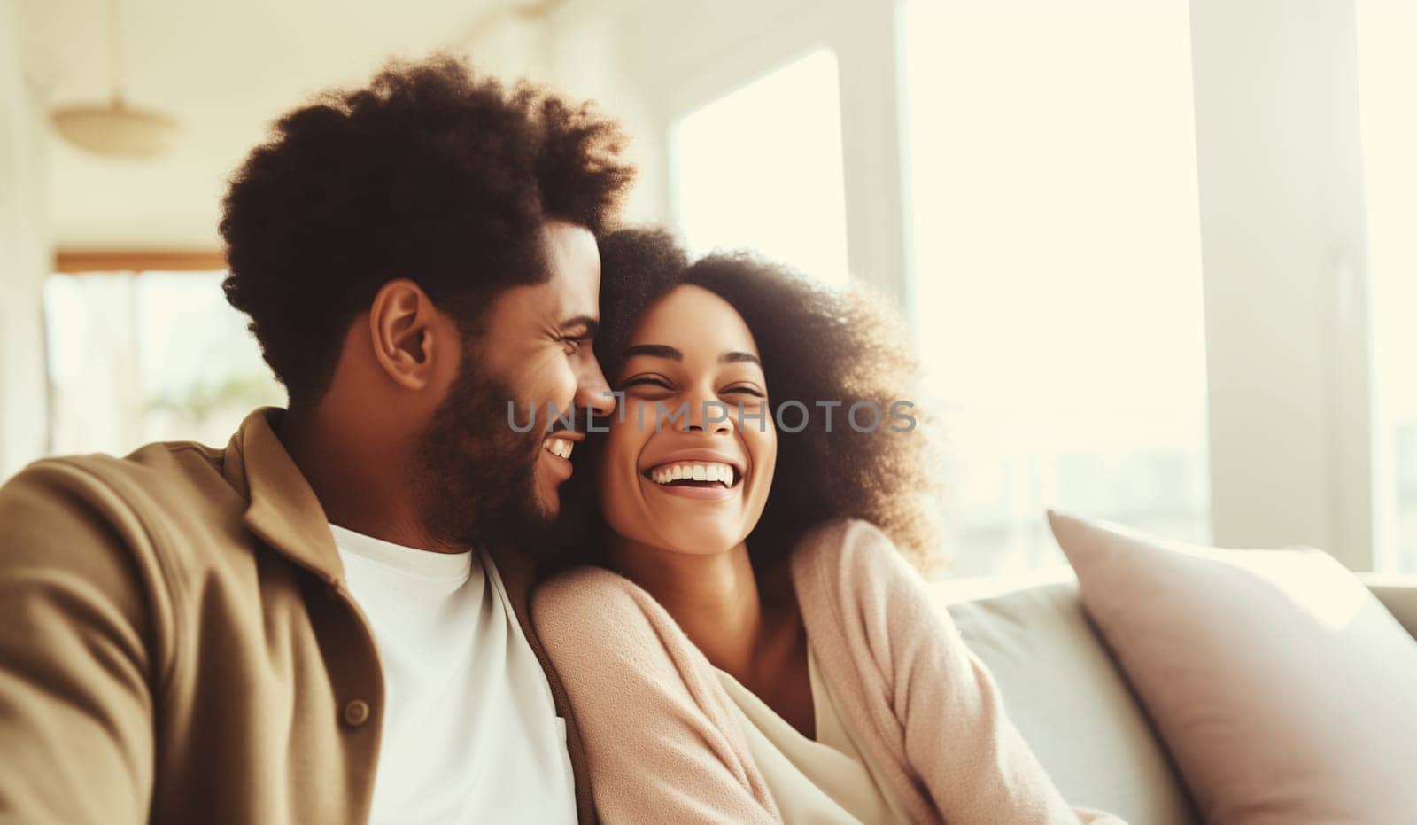 Portrait of happy smiling african young couple hugging, cheerful black woman and man sitting on sofa at home together