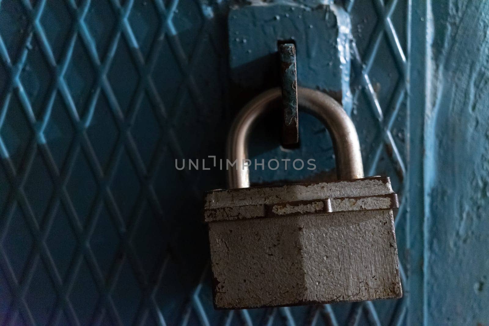 A large lock on the door made of iron painted with blue paint.