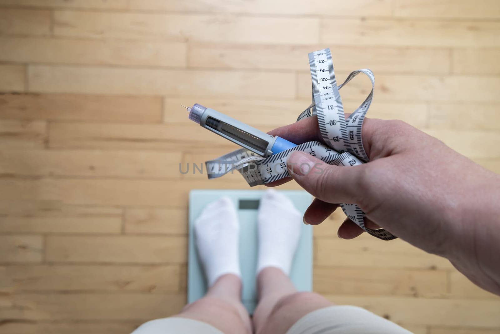 Ozempic Insulin injection pen for diabetics and weight loss. Woman weighs herself and holds Ozempic in her hand. Weight loss concept.