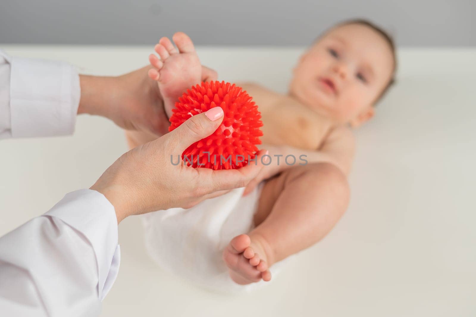 A doctor massages a baby's foot using a spiked ball