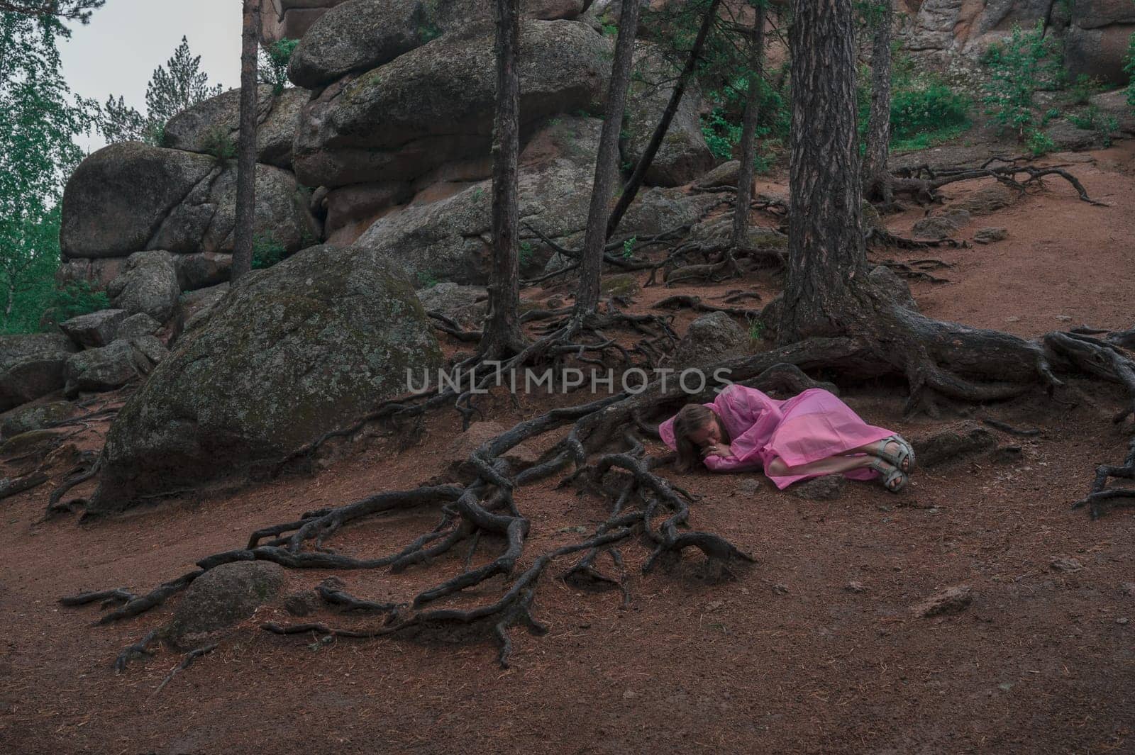 Woman in raincoat in the taiga forest and rocks of the Stolby nature reserve park, Krasnoyarsk, Russia