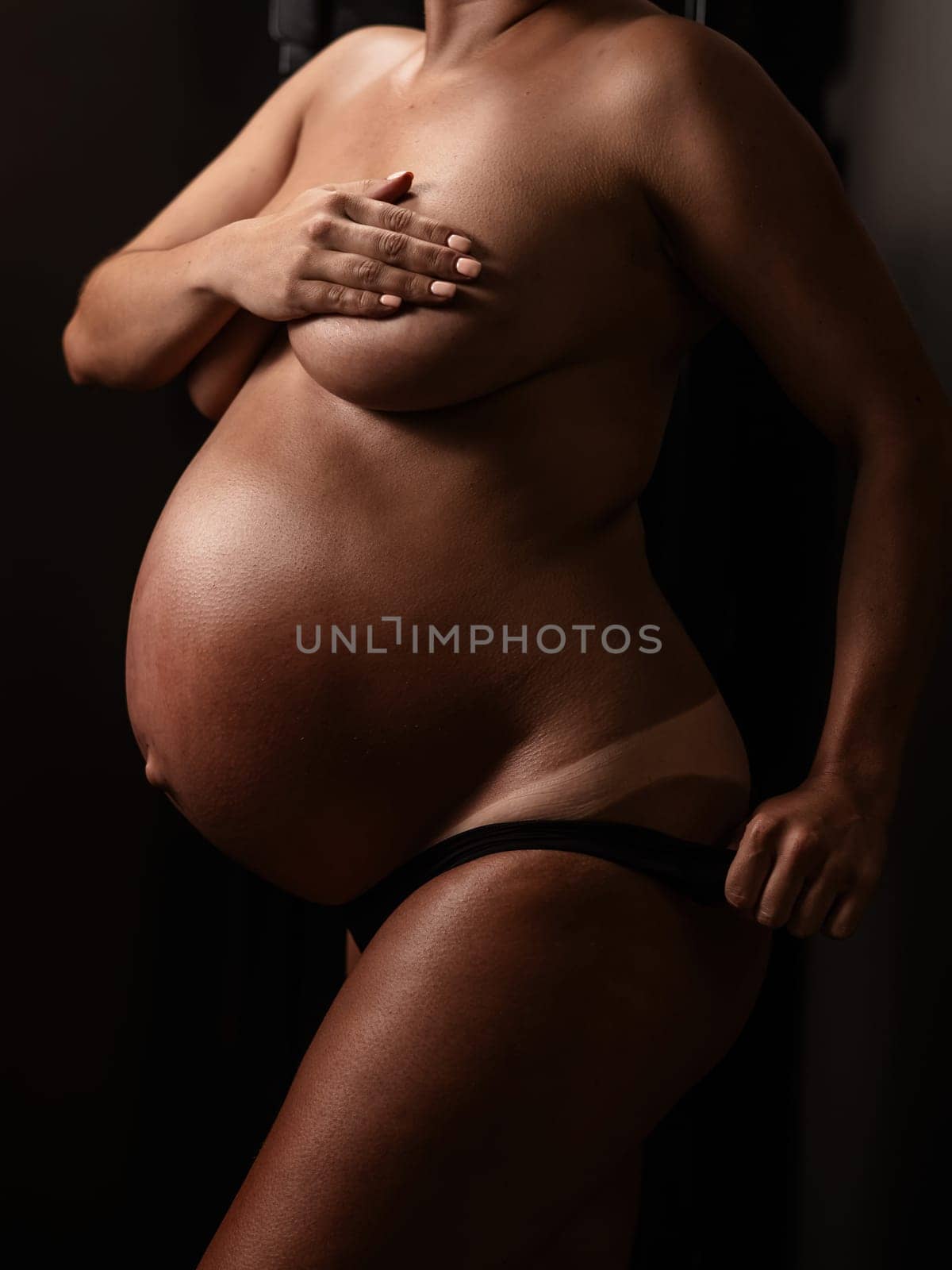 Pregnant woman pulls back her panties showing instant tan. Vertical photo. by mrwed54