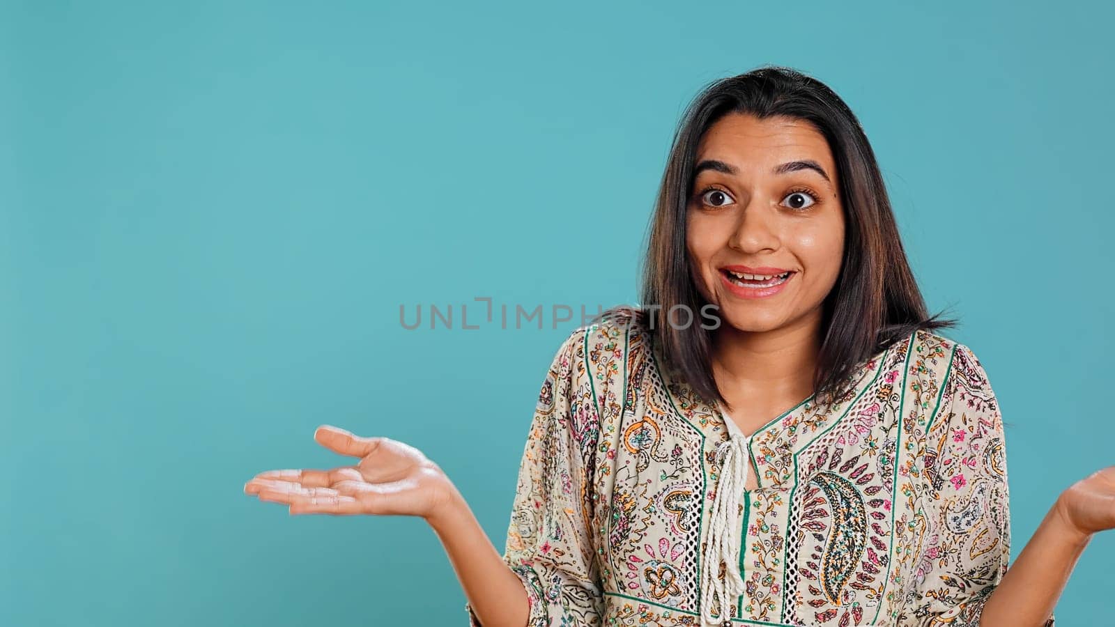 Indian woman shrugging shoulders, unable to provide answer, having detached apathy facial expression. Apathetic person doing hand gesturing showing lack of knowledge, studio background, camera B