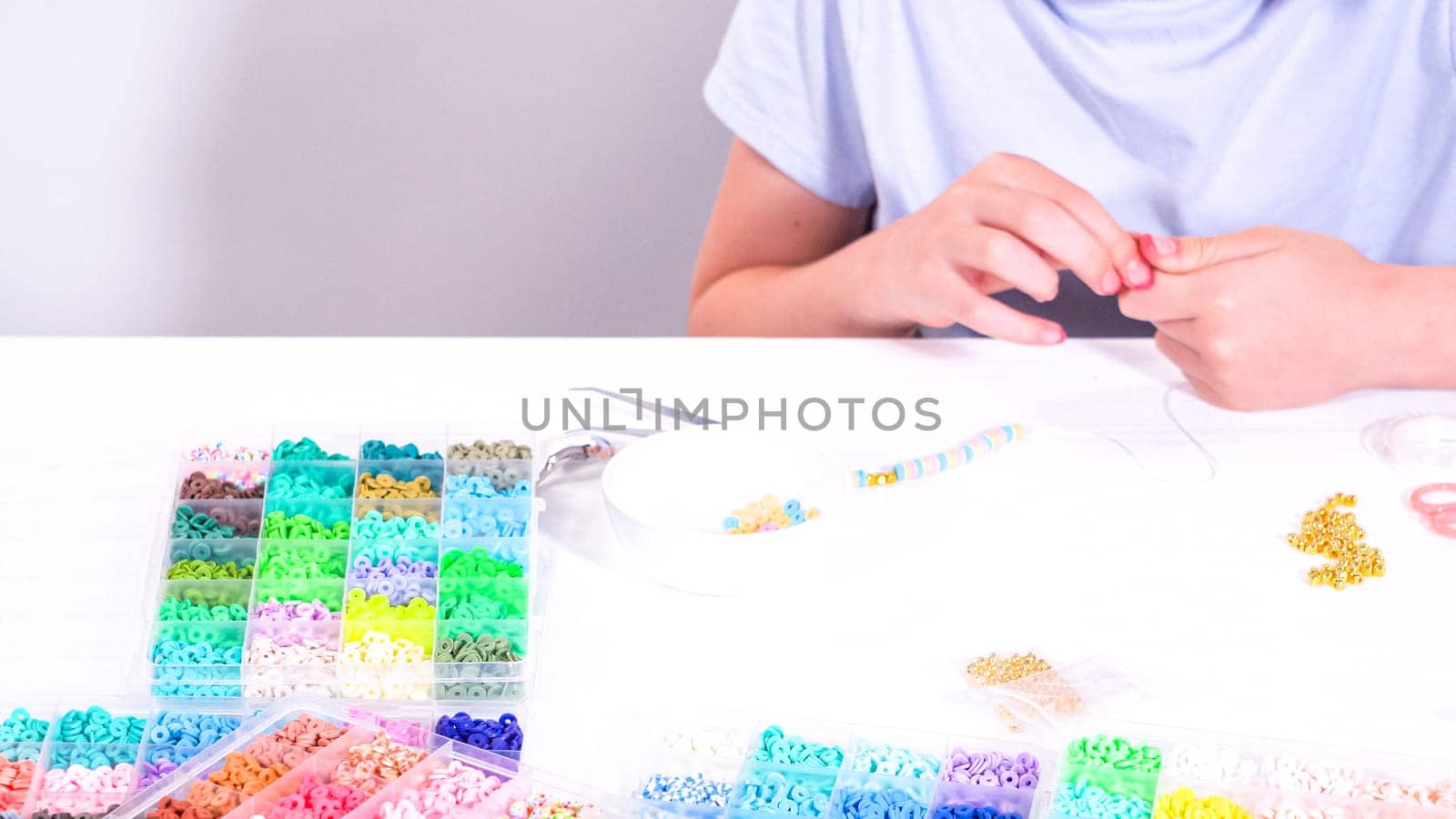 Delicate fingers of a young girl navigate through a treasure trove of bright, multicolored beads, each compartment revealing a new hue to choose from.