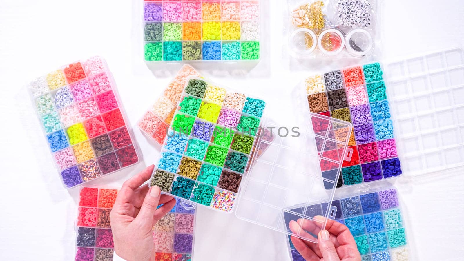 Woman's Hands Amidst a Rainbow Array of Beads for Jewelry Crafting by arinahabich