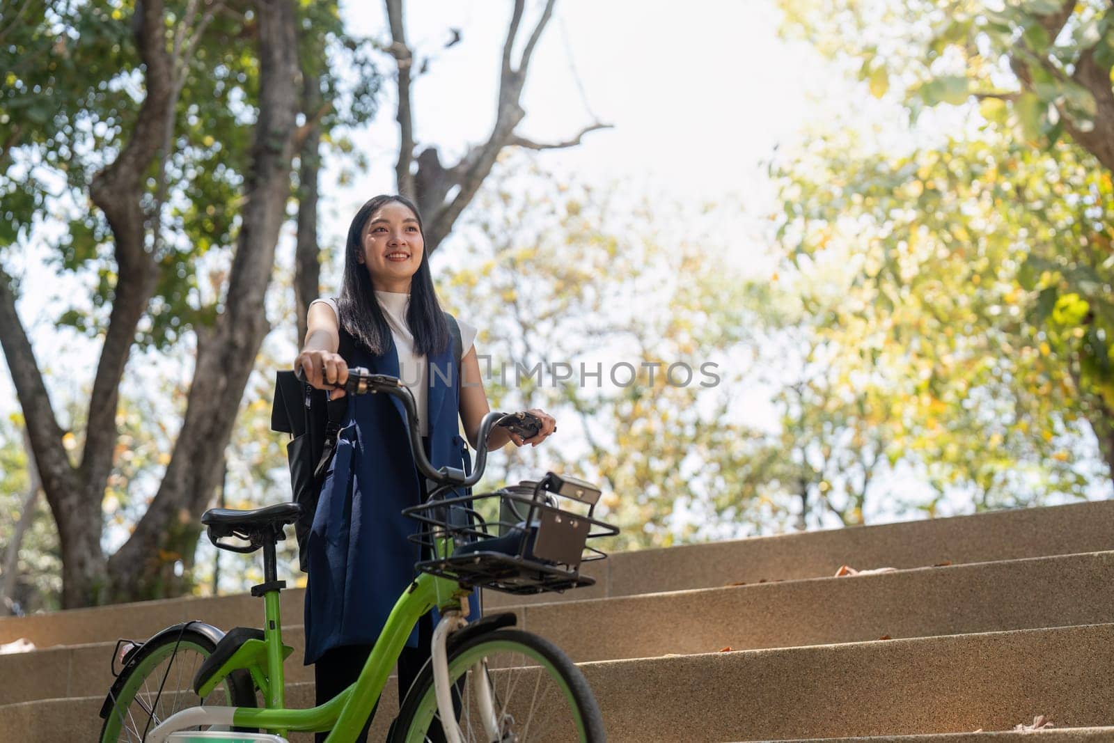 Smiling Asian woman standing outdoors with her bicycle, promoting eco-friendly commuting and a healthy lifestyle