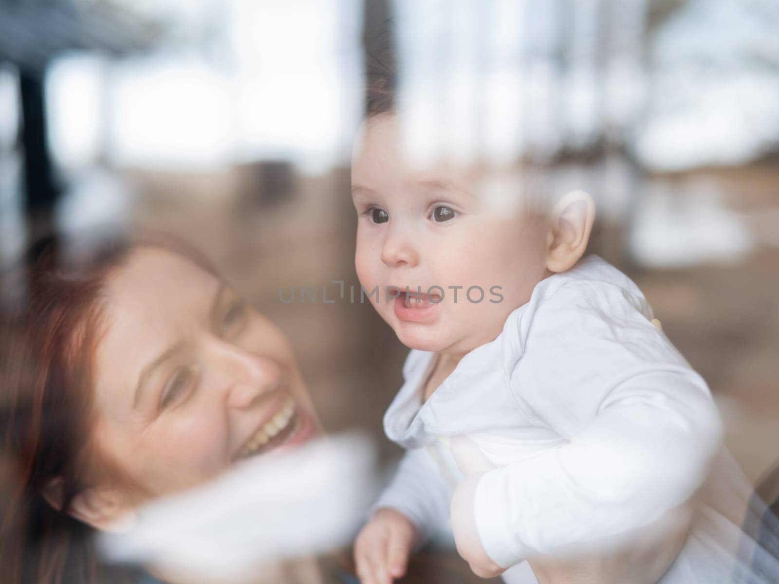 View through the window of a red-haired Caucasian woman holding her little son