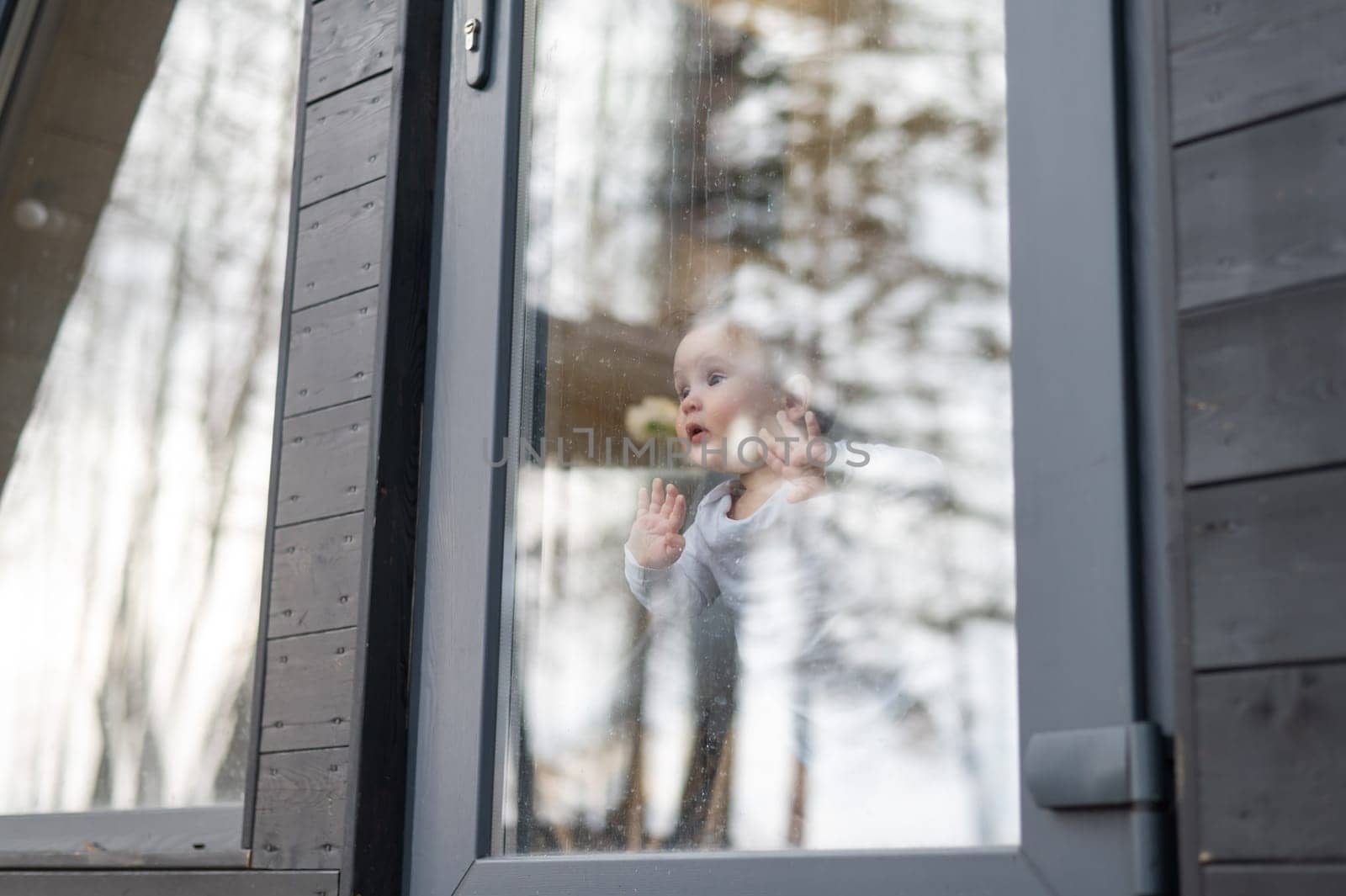 Baby boy standing by the patio window