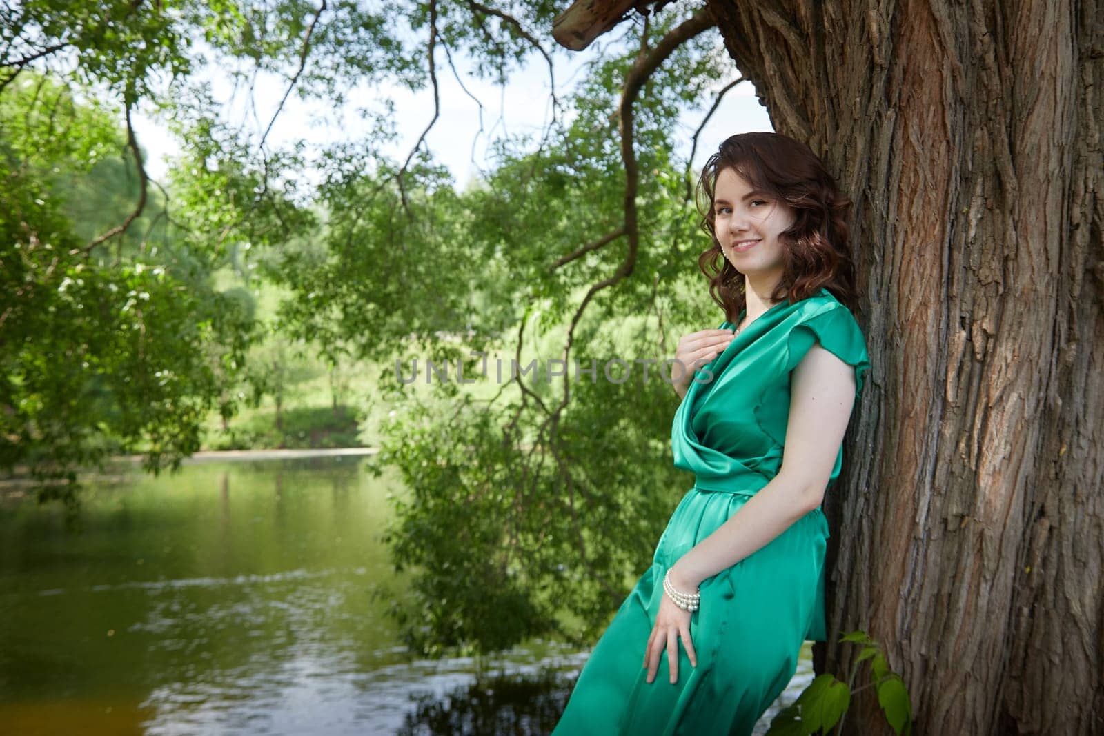 Portrait of a happy girl in the park in summer. Holidays, rest, youth. A young girl with curly hair in a green park on a summer day