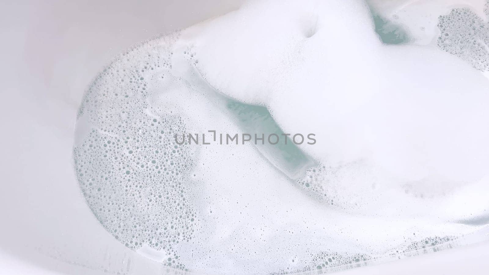 Modern White Bathtub Filled with Running Water from a Brushed Nickel Faucet by arinahabich