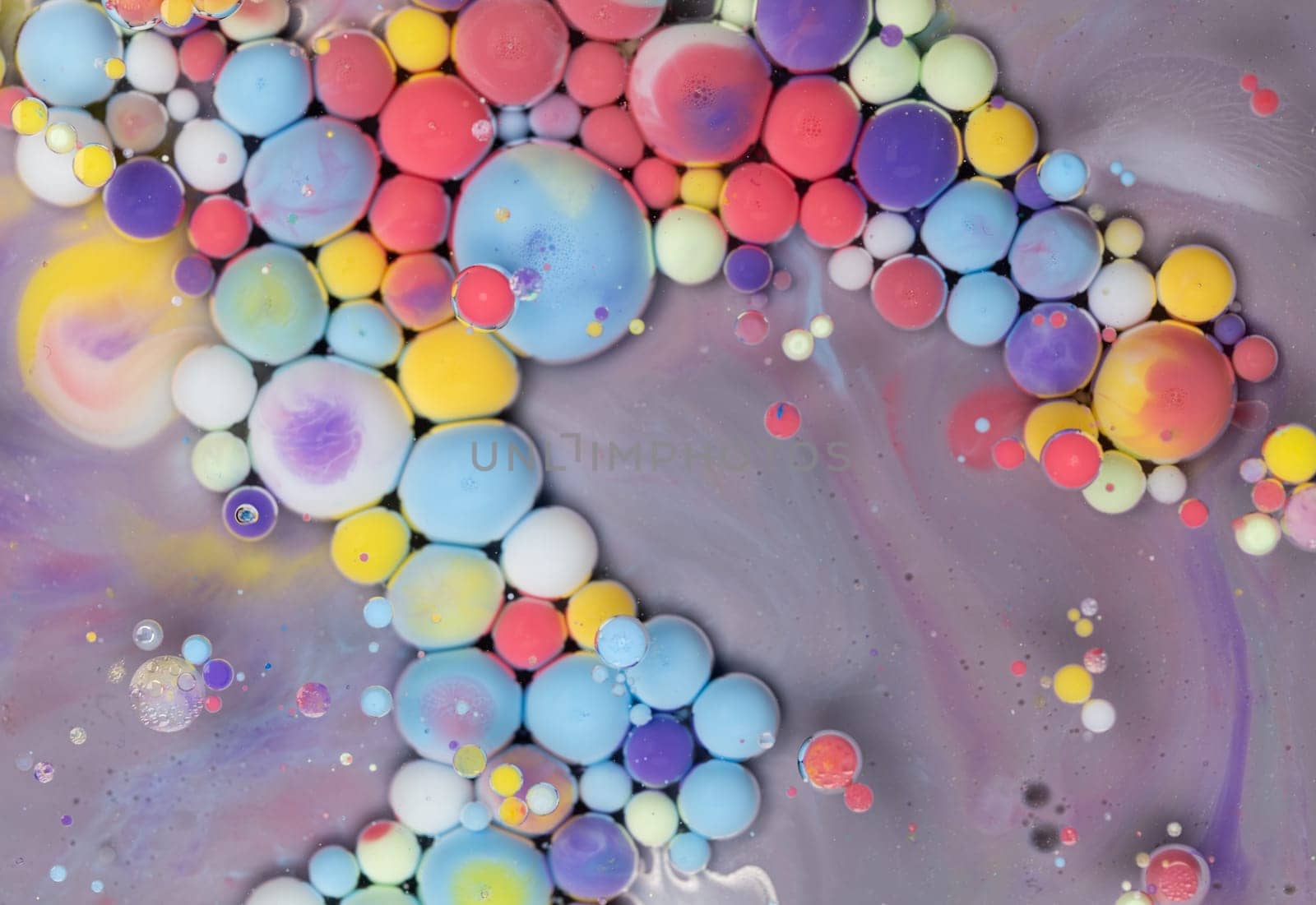 A close-up photograph showcasing a mesmerizing array of colorful bubbles suspended in a liquid medium, creating a stunning abstract composition. The bubbles exhibit a vibrant spectrum of hues.