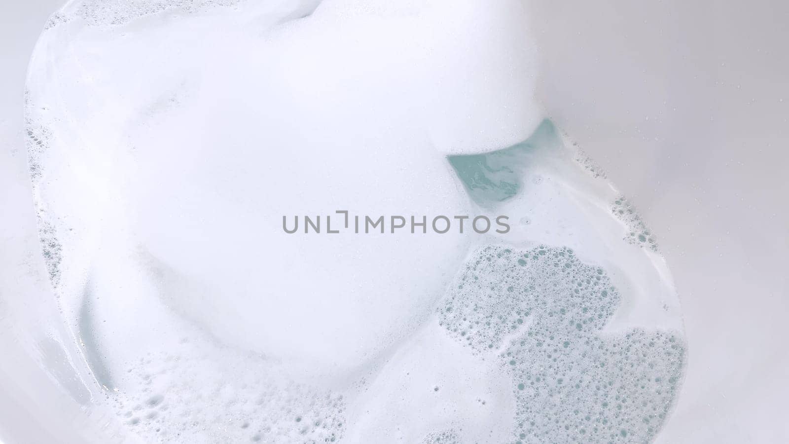 Modern White Bathtub Filled with Running Water from a Brushed Nickel Faucet by arinahabich