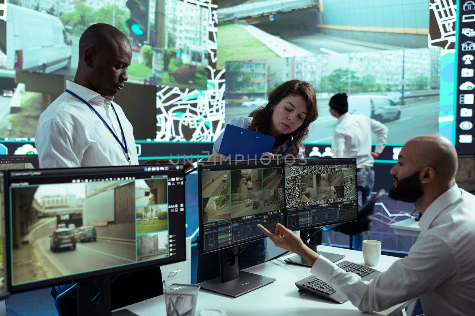 Diverse team of supervisors overseeing their staff activity on gps locating, following delivery truck drivers around in traffic via satellite map. Operators guiding couriers on routes.