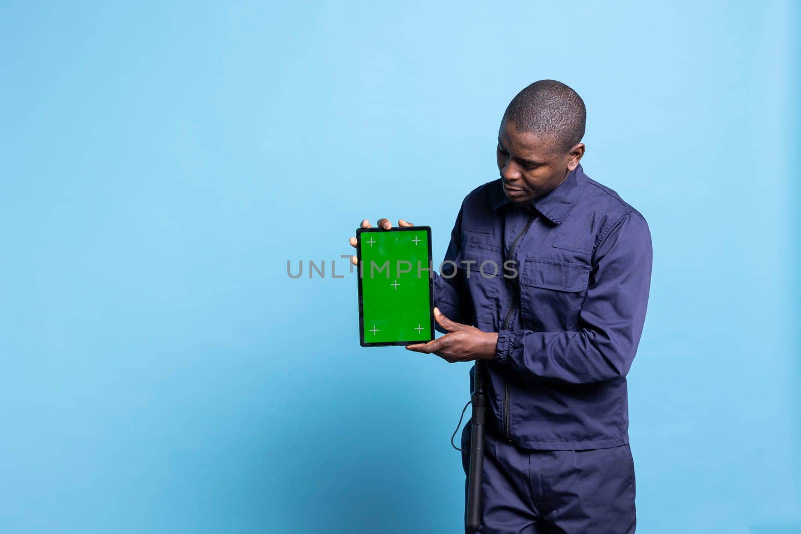 Trained armed bodyguard holds a tablet with greenscreen layout on camera by DCStudio