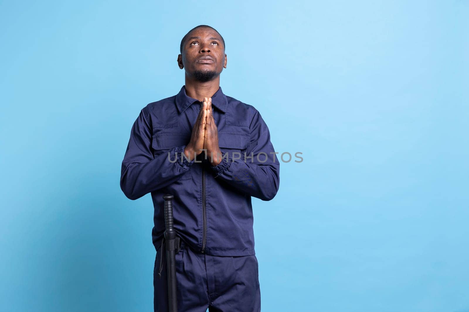 Religious security agent praying to God and having faith against blue background by DCStudio