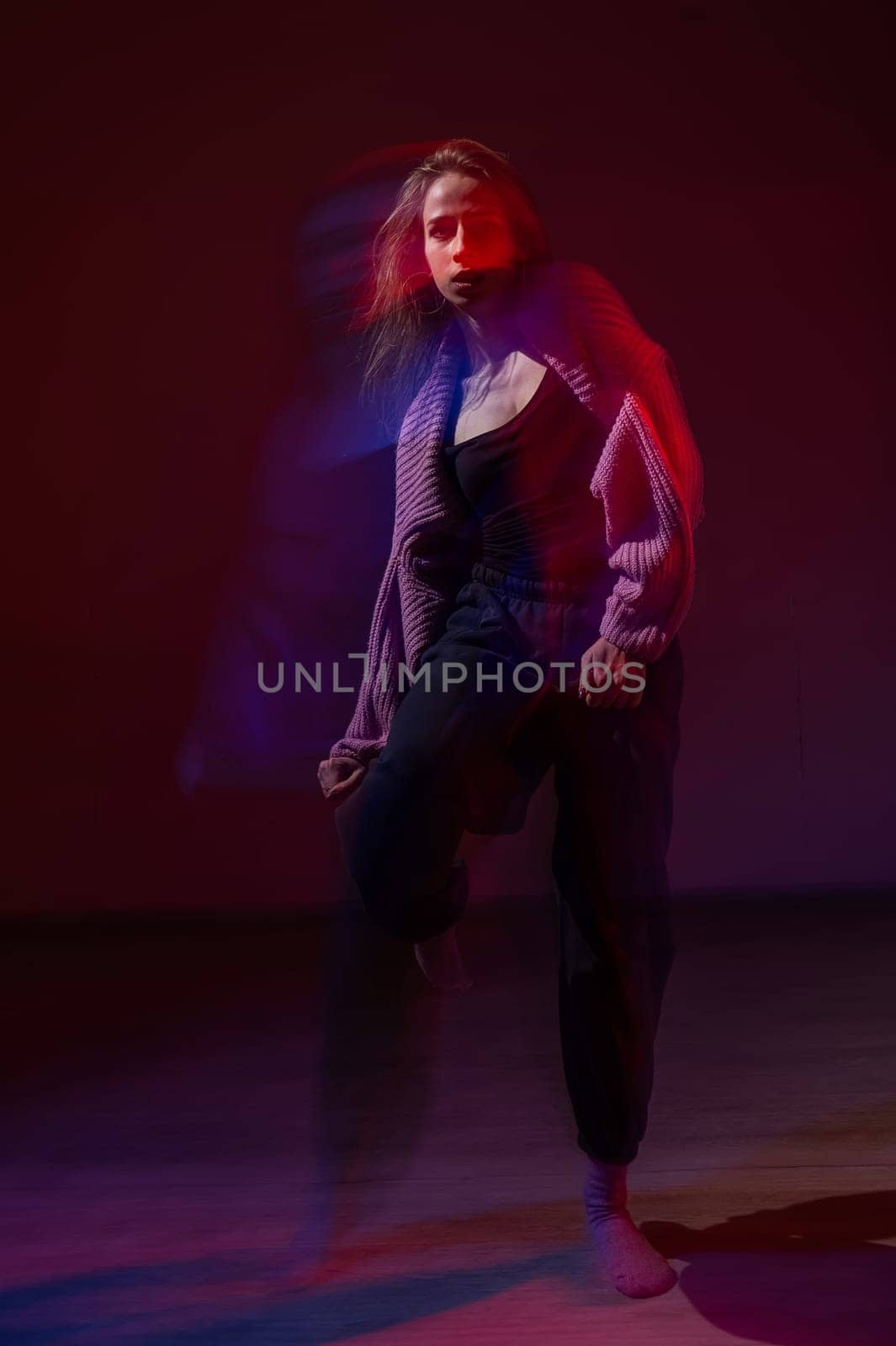 A young woman dances contemporary dances in blue and red light. Long exposure. Vertical photo. by mrwed54