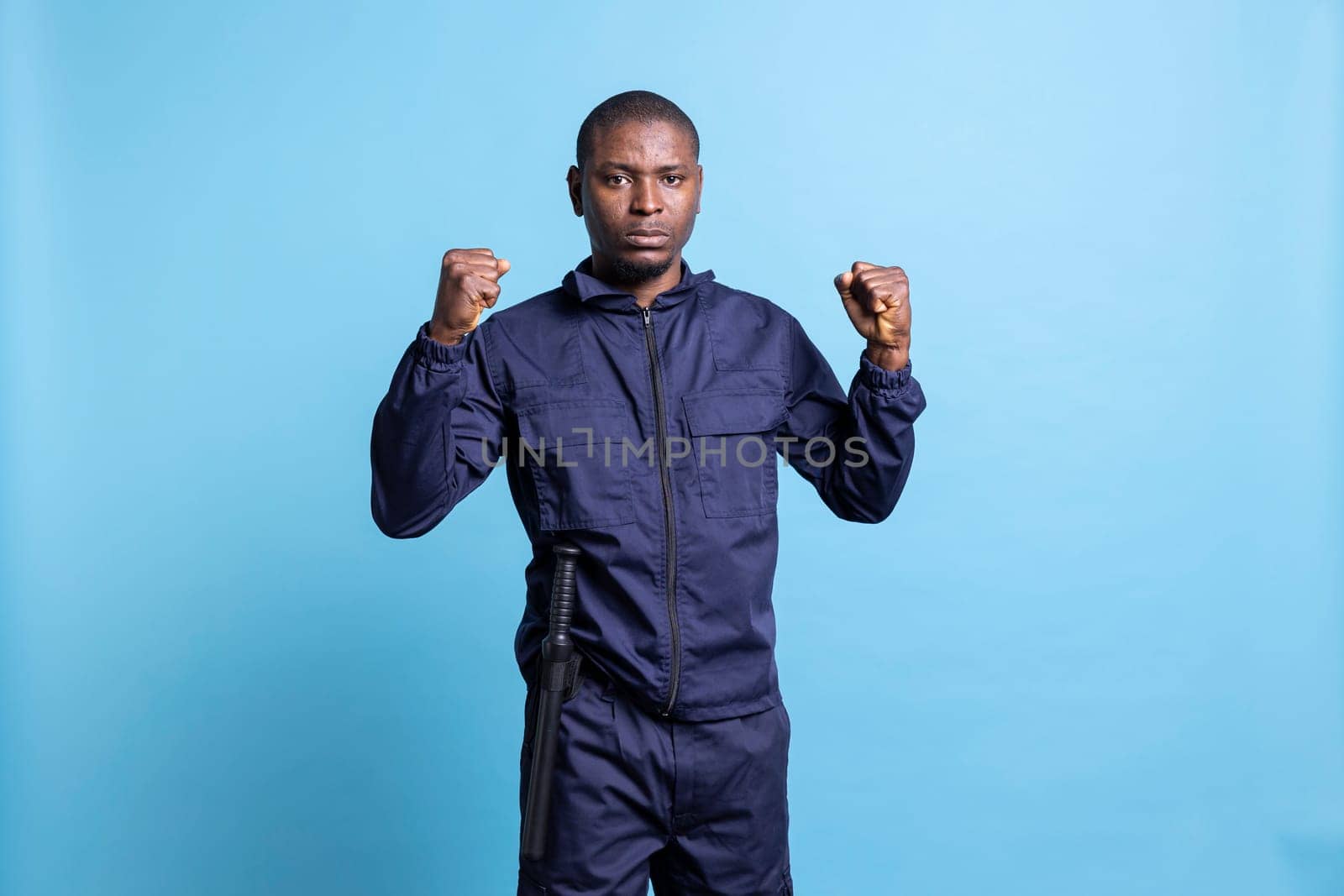 Confident security guard is clenching his fists in front of the camera, prepared for a fight in order to protect and safeguard a property. Armed agent with proper protection training.