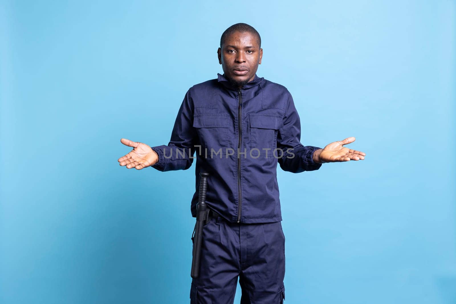 Clueless unsure security officer shrugging against blue background by DCStudio