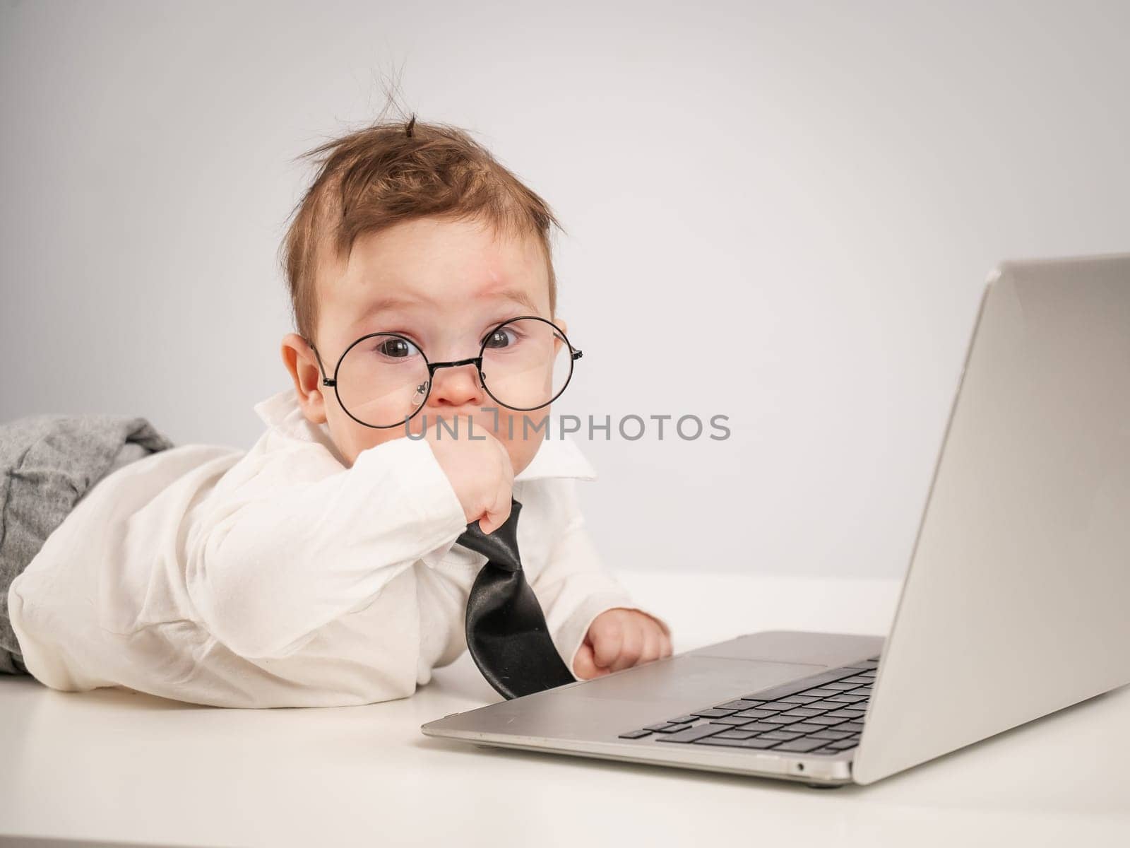 Cute baby in glasses and suit working on laptop. by mrwed54