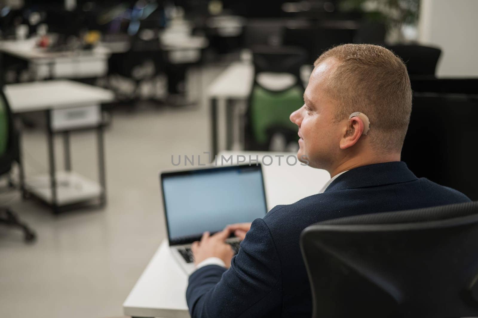 Caucasian deaf man typing on laptop in office
