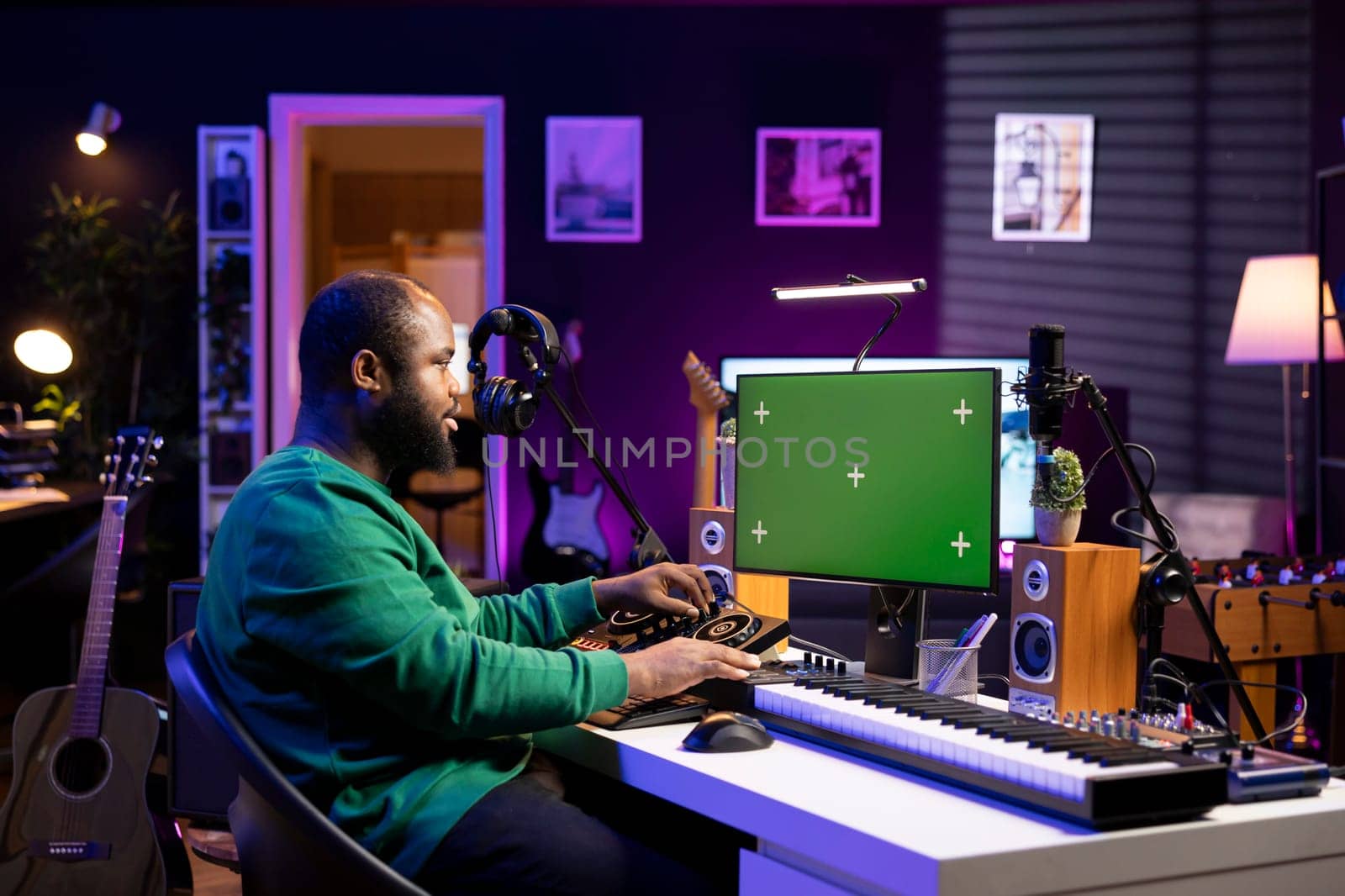 Audio technician creating new tunes on his mixing console, using pc with isolated mockup screen. Producer adjusting volume levels on his recordings to launch new music in his home studio.