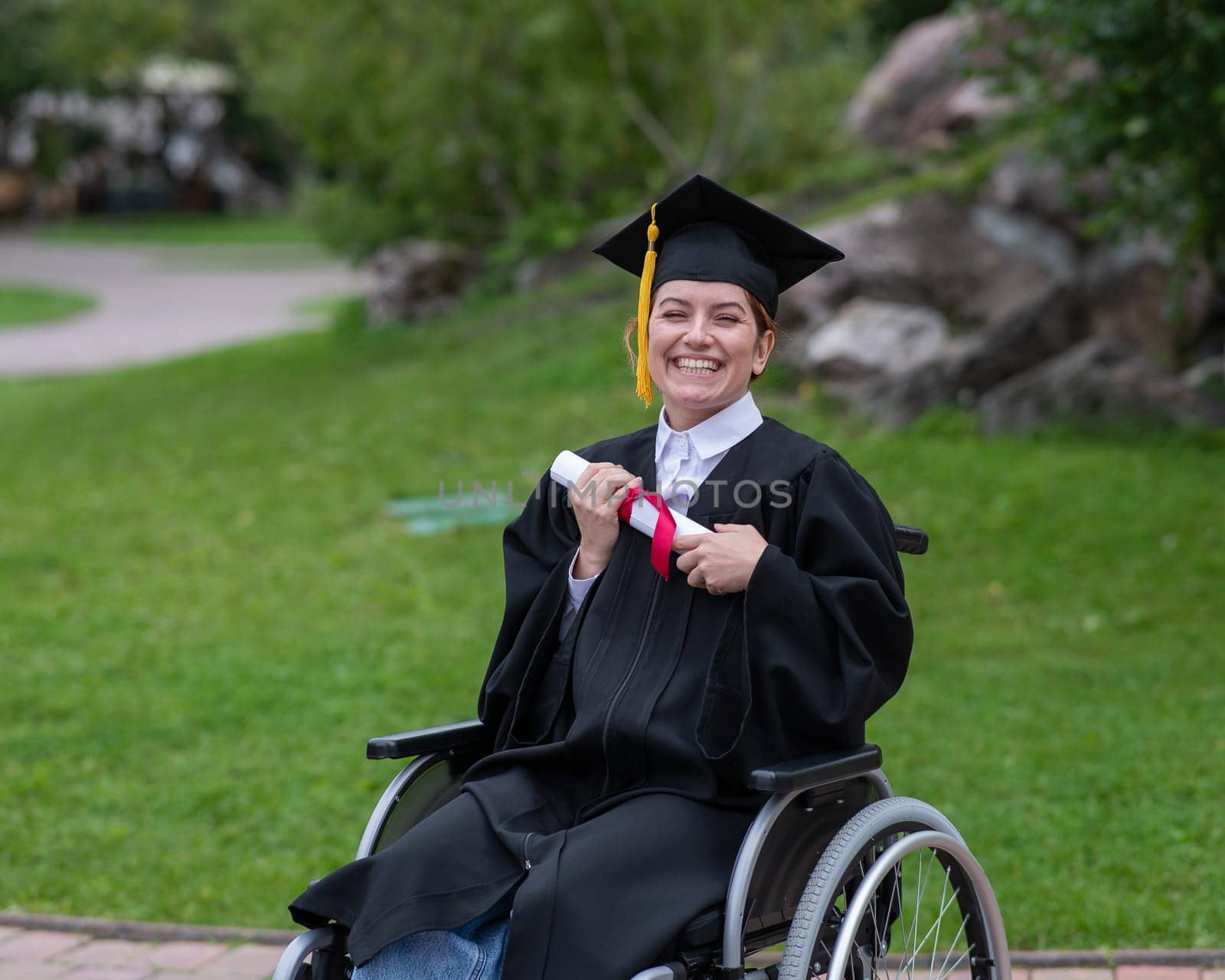 Happy caucasian woman in a wheelchair holding her diploma outdoors. by mrwed54