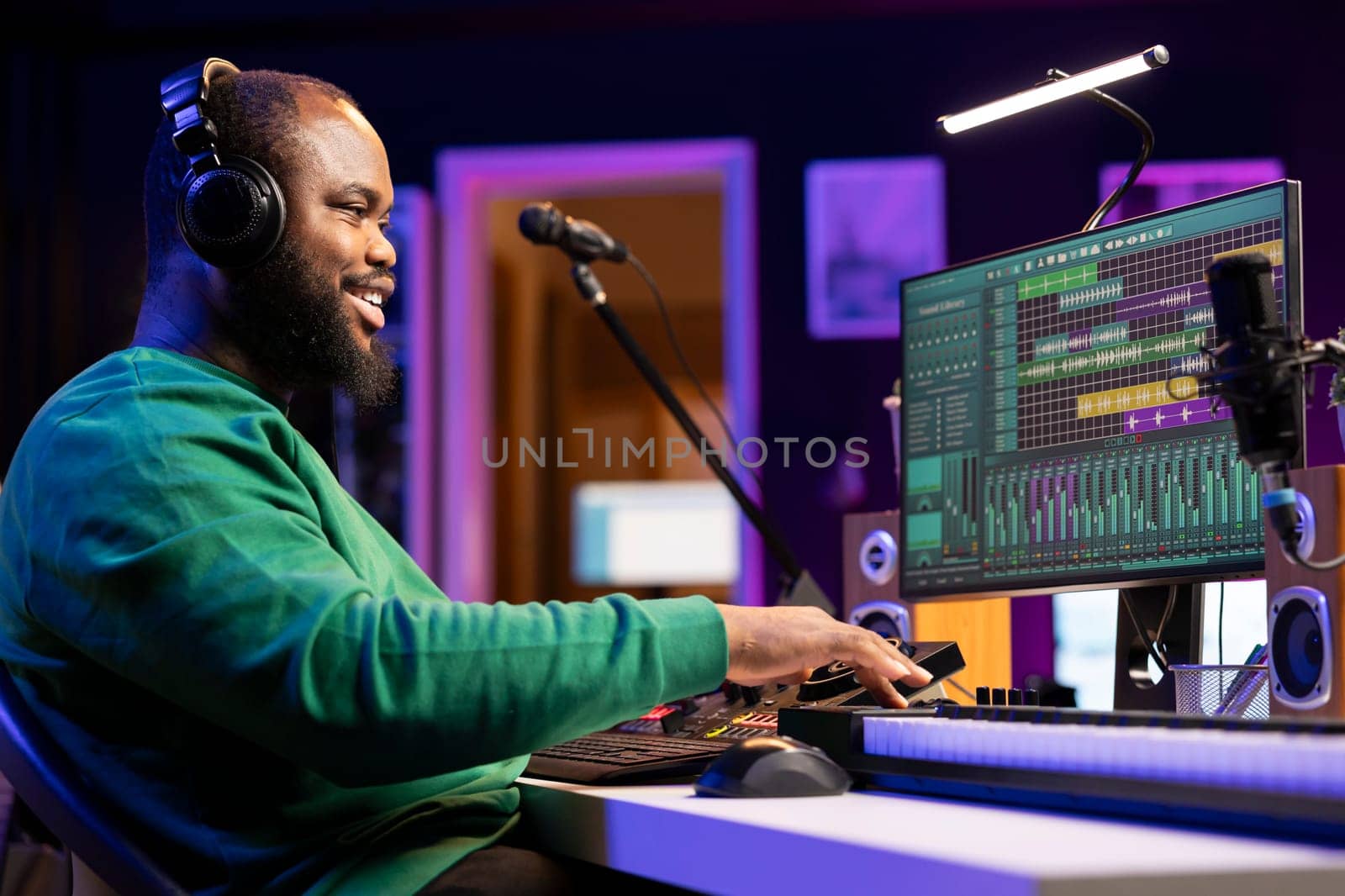 Sound engineer working with mixing console and synthesizer to edit his audio files, using digital software interface for mix and master session in post production. Musician launching an album.