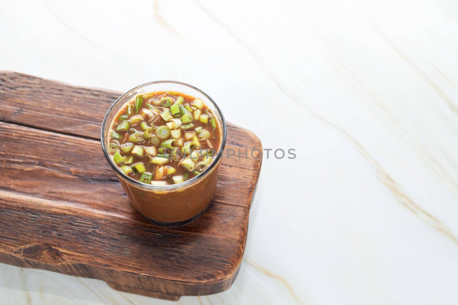 Spring Onion Coffee Or Scallion Coffee on Wooden Tray. Popular Beverage In China. Top View Glass Of Drink, Cappuccino Or Latte With Onions On Granite Table. Copy Space. Horizontal Plane
