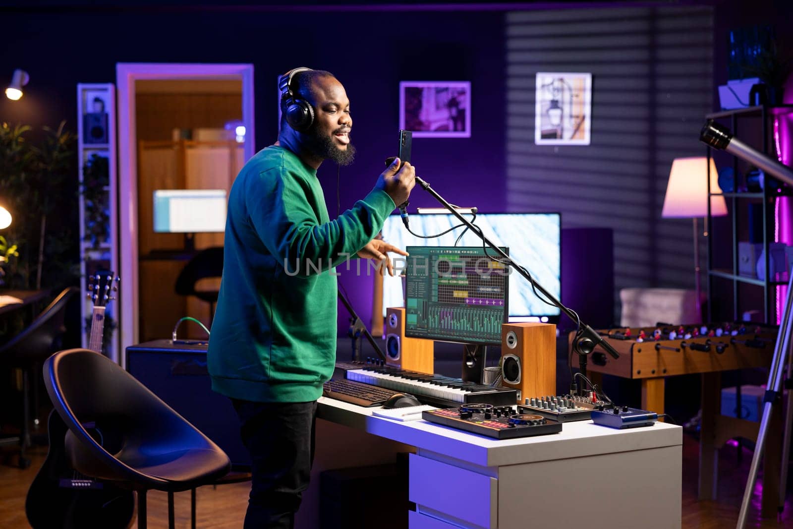 Talented composer artist does a recording session for his acoustic tunes, performing on microphone in home studio. Confident singer working on producing new soundtracks for an album.