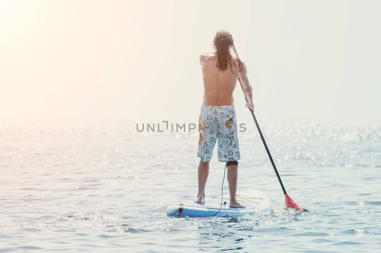 Man Sea Sup. Strong athletic man learns to paddle sup standing on board in open sea ocean on sunny day. Summer holiday vacation and travel concept. Aerial view. Slow motion.